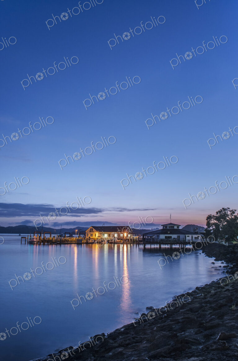 Illuminated buildings on water at dawn