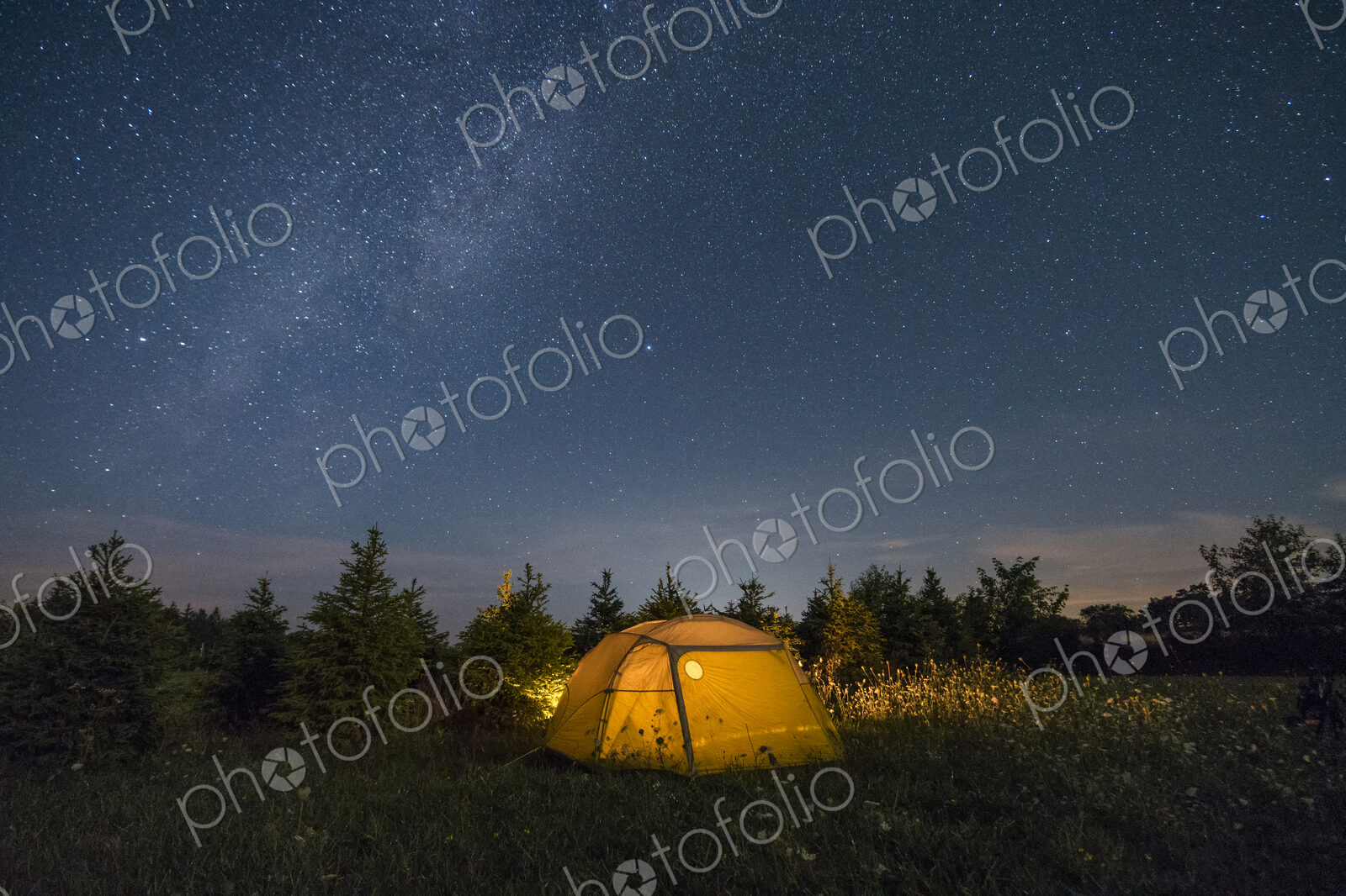 Illuminated camping tent under starry sky