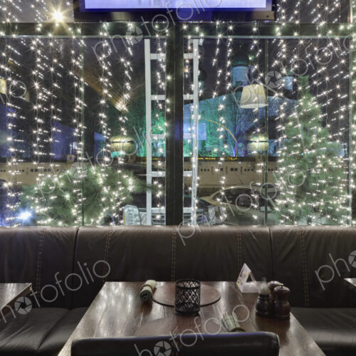 Illuminated restaurant window at night, with tables and chairs. Illuminated restaurant window at night, with tables and chairs.