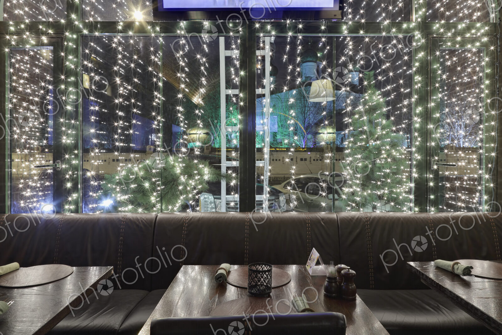 Illuminated restaurant window at night, with tables and chairs.