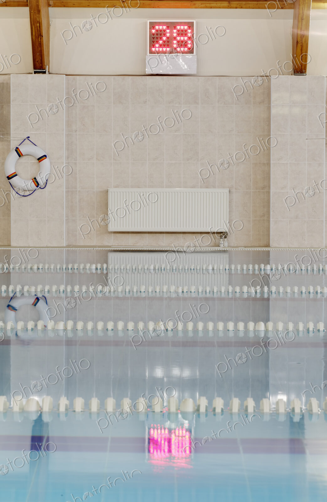 Indoor heated swimming pool, lifering and wall thermometer display, pink float in the…