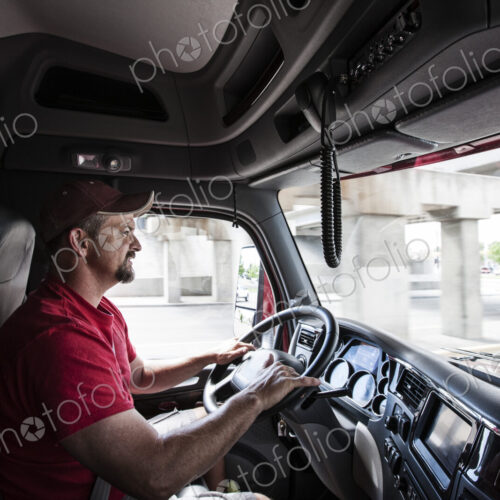 Interior cab view of a Caucasian man driving his commercial truck. Interior cab view of a Caucasian man driving his commercial truck.