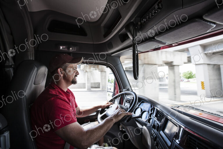 Interior cab view of a Caucasian man driving his commercial truck.