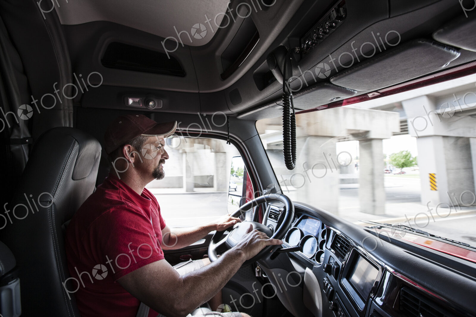 Interior cab view of a Caucasian man driving his commercial truck.