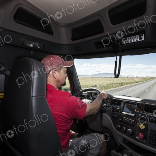 Interior cab view of a Caucasian man driving his commercial truck. Interior cab view of a Caucasian man driving his commercial truck.