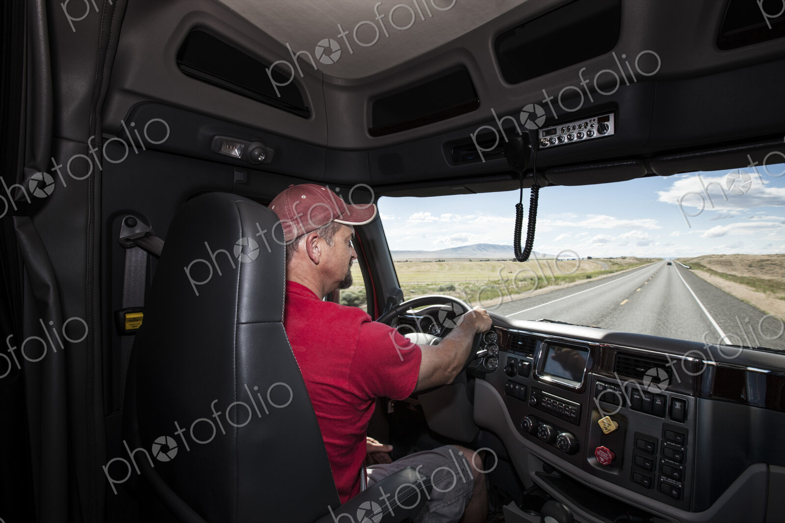 Interior cab view of a Caucasian man driving his commercial truck.