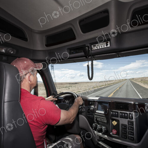 Interior cab view of a Caucasian man driving his commercial truck. Interior cab view of a Caucasian man driving his commercial truck.