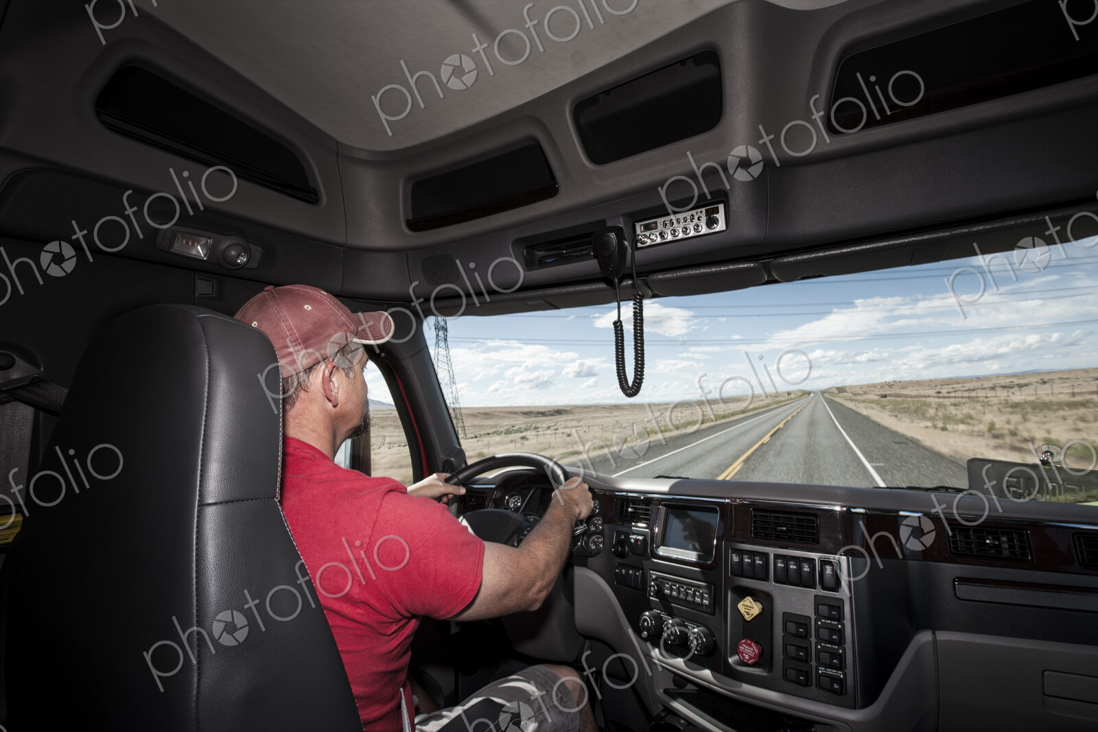 Interior cab view of a Caucasian man driving his commercial truck.