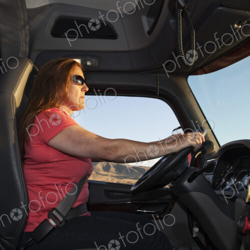 Interior cab view of a Caucasian woman driver driving her commercial truck. Interior cab view of a Caucasian woman driver driving her commercial truck.