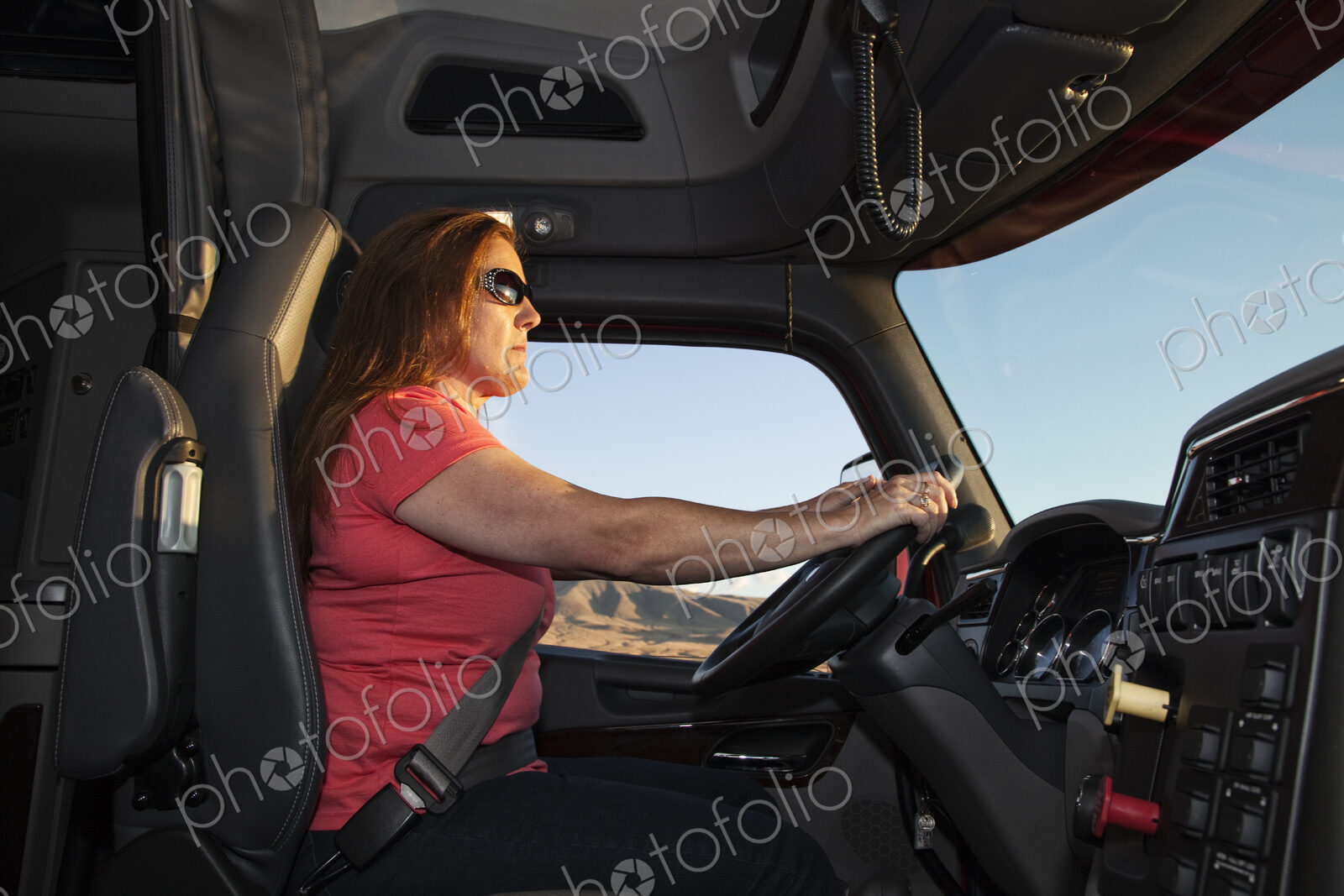 Interior cab view of a Caucasian woman driver driving her commercial truck.
