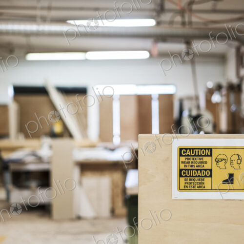 Interior of a woodworking factory showing a sign for safety gear regulations.