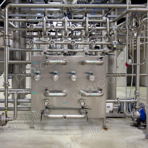 Interior of brewery, large steel pipes, valves and control unit for the brewing process