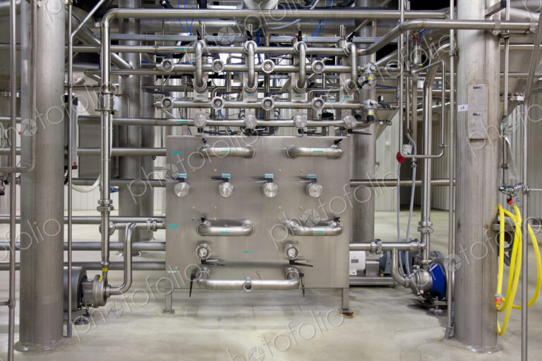 Interior of brewery, large steel pipes, valves and control unit for the brewing process