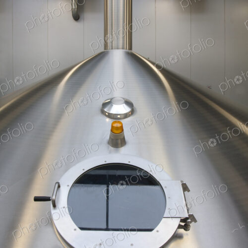 Interior of brewery, large steel storage tanks for brewing beer, inspection hatch