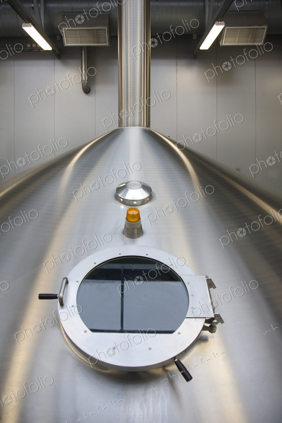 Interior of brewery, large steel storage tanks for brewing beer, inspection hatch