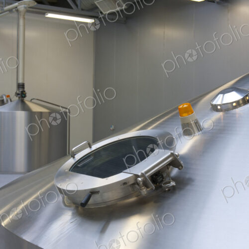 Interior of brewery, large steel storage tanks for brewing beer, inspection hatch