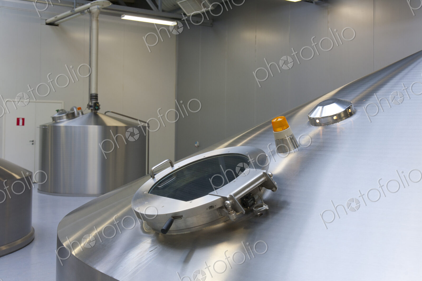Interior of brewery, large steel storage tanks for brewing beer, inspection hatch