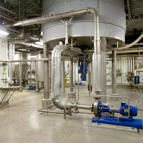 Interior of brewery, large steel storage tanks for brewing beer with metal pipes and…