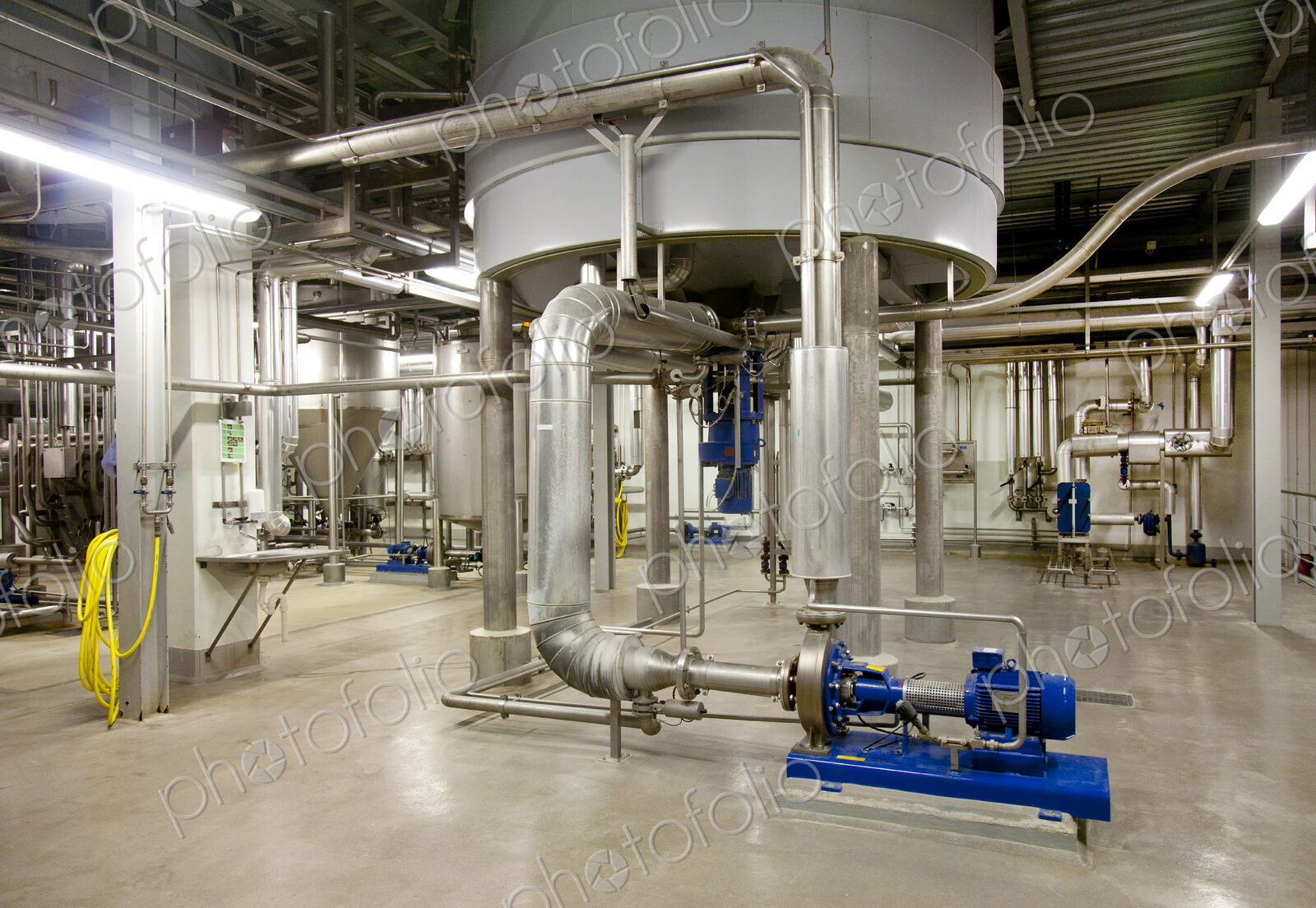 Interior of brewery, large steel storage tanks for brewing beer with metal pipes and…