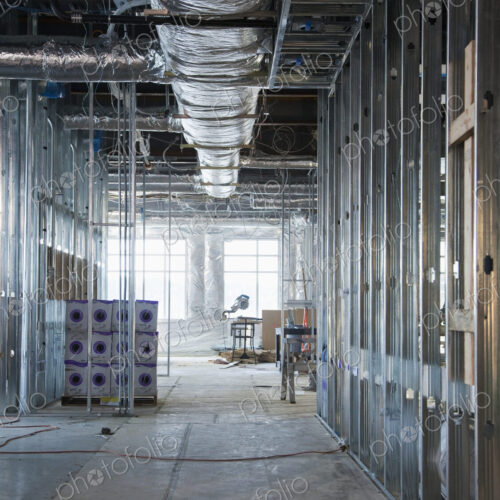 Interior of construction site with exposed ducts and metal joists.