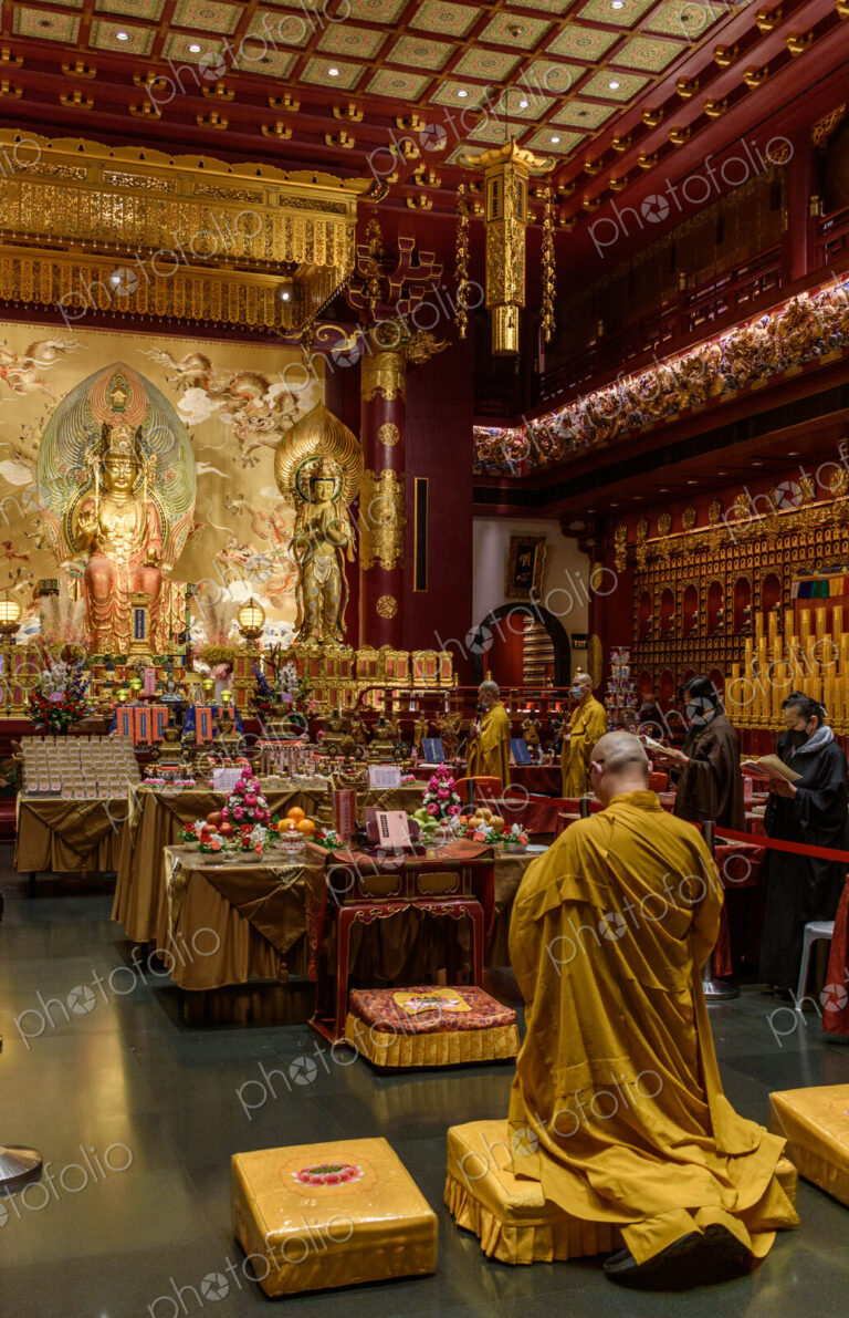 Interior view of a Buddhist Temple in Singapore, worshippers and statues of the buddha.