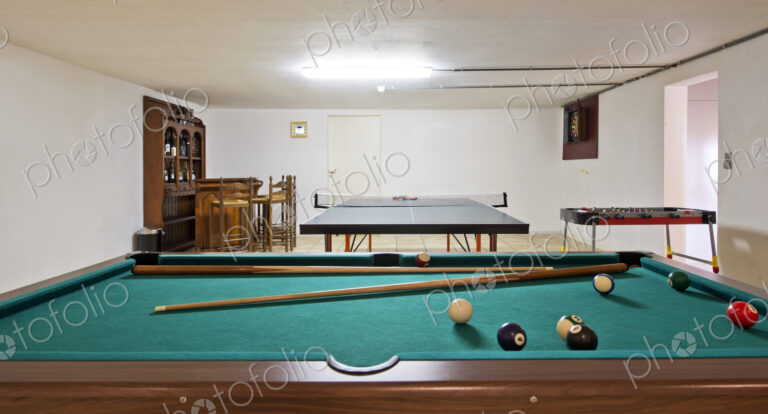 Interior view of a basement room with pool billiard and ping pong tables.