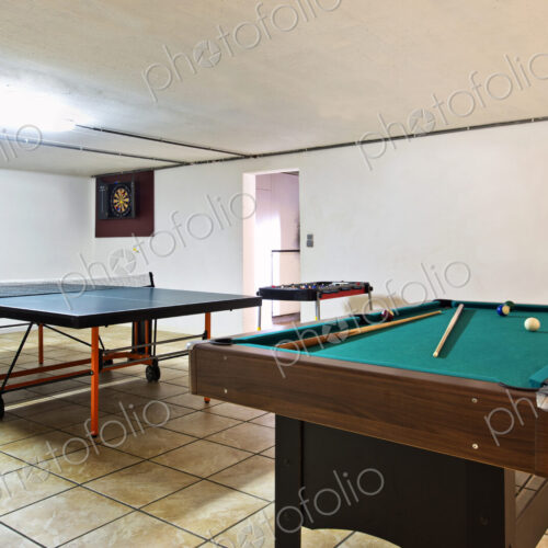 Interior view of a basement room with pool billiard and ping pong tables. Interior view of a basement room with pool billiard and ping pong tables.