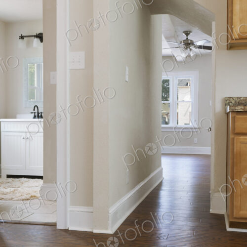Interior view of a bathroom, kitchen and hallway with neutral decor and colour scheme.