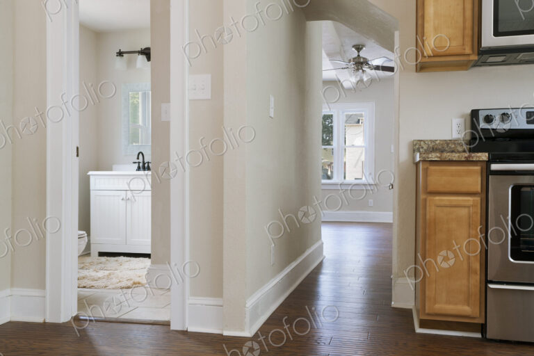 Interior view of a bathroom, kitchen and hallway with neutral decor and colour scheme.