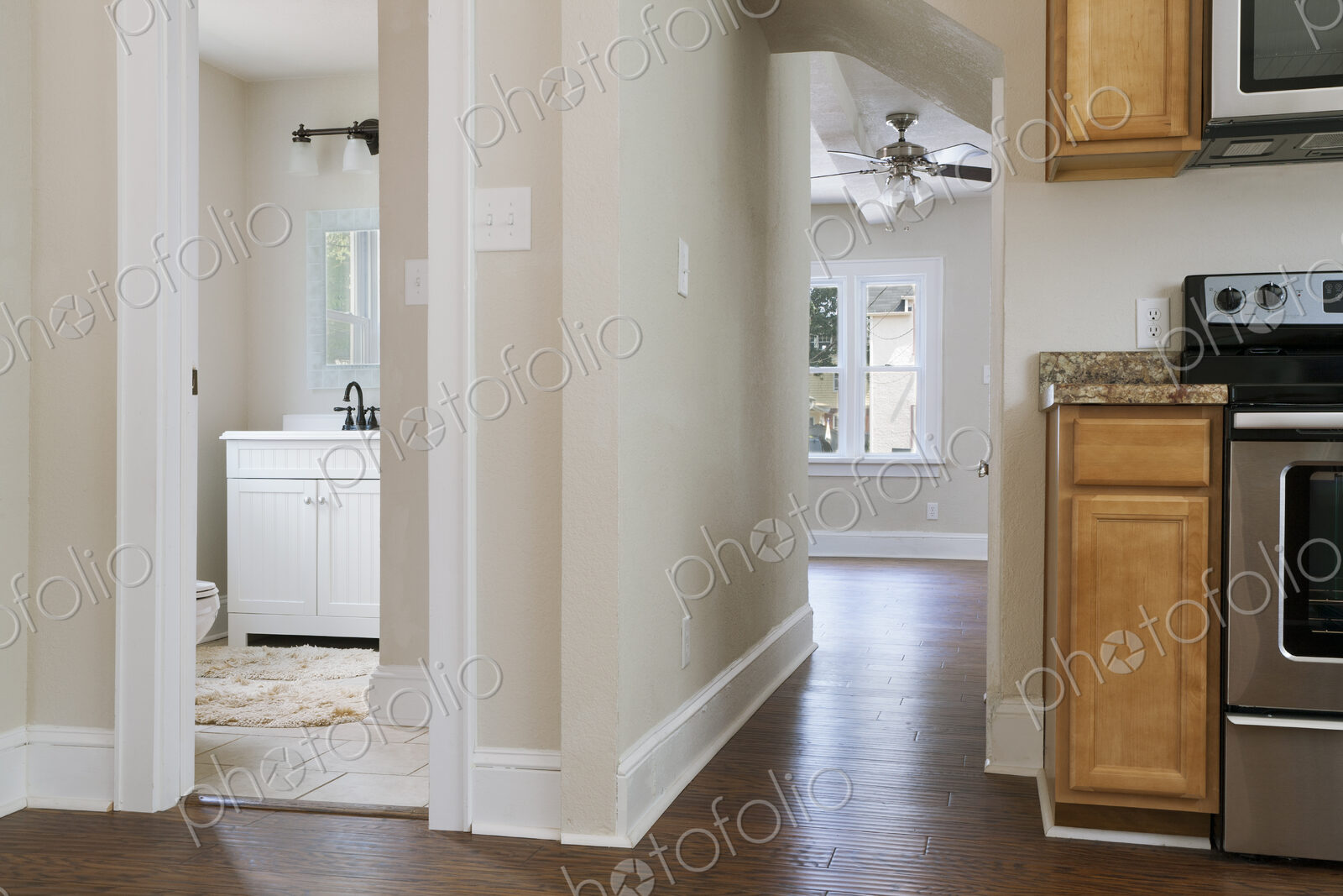 Interior view of a bathroom, kitchen and hallway with neutral decor and colour scheme.