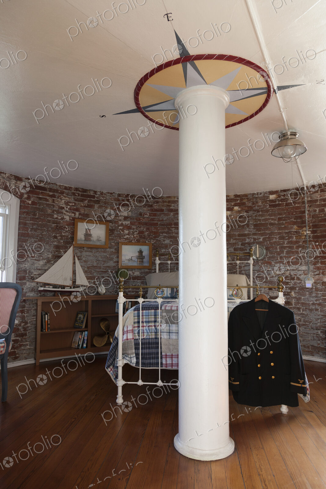Interior view of a bedroom with exposed brick walls and metal bed in a lighthouse,…