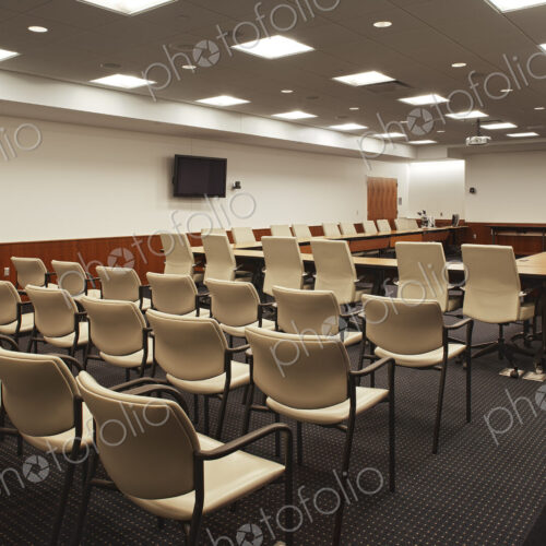 Interior view of a lecture hall or meeting room, a large conference table with a…