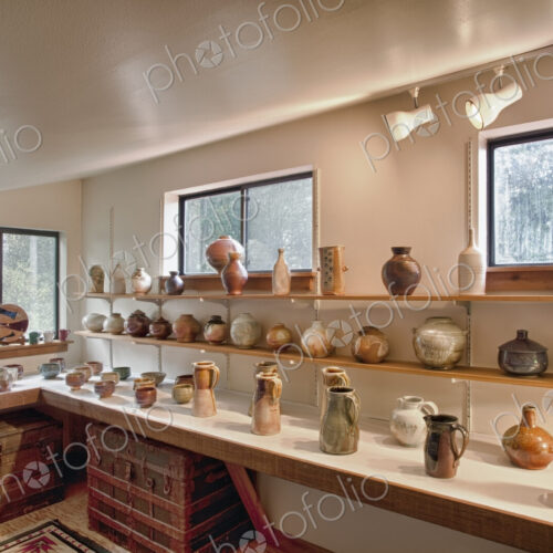 Interior view of a potter's workshop, rows of completed ceramic work, vases and pots…