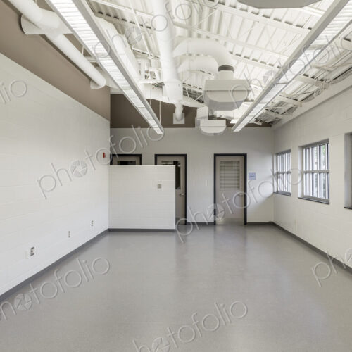 Interior view of a room with white walls and grey vinyl floor in an animal shelter.