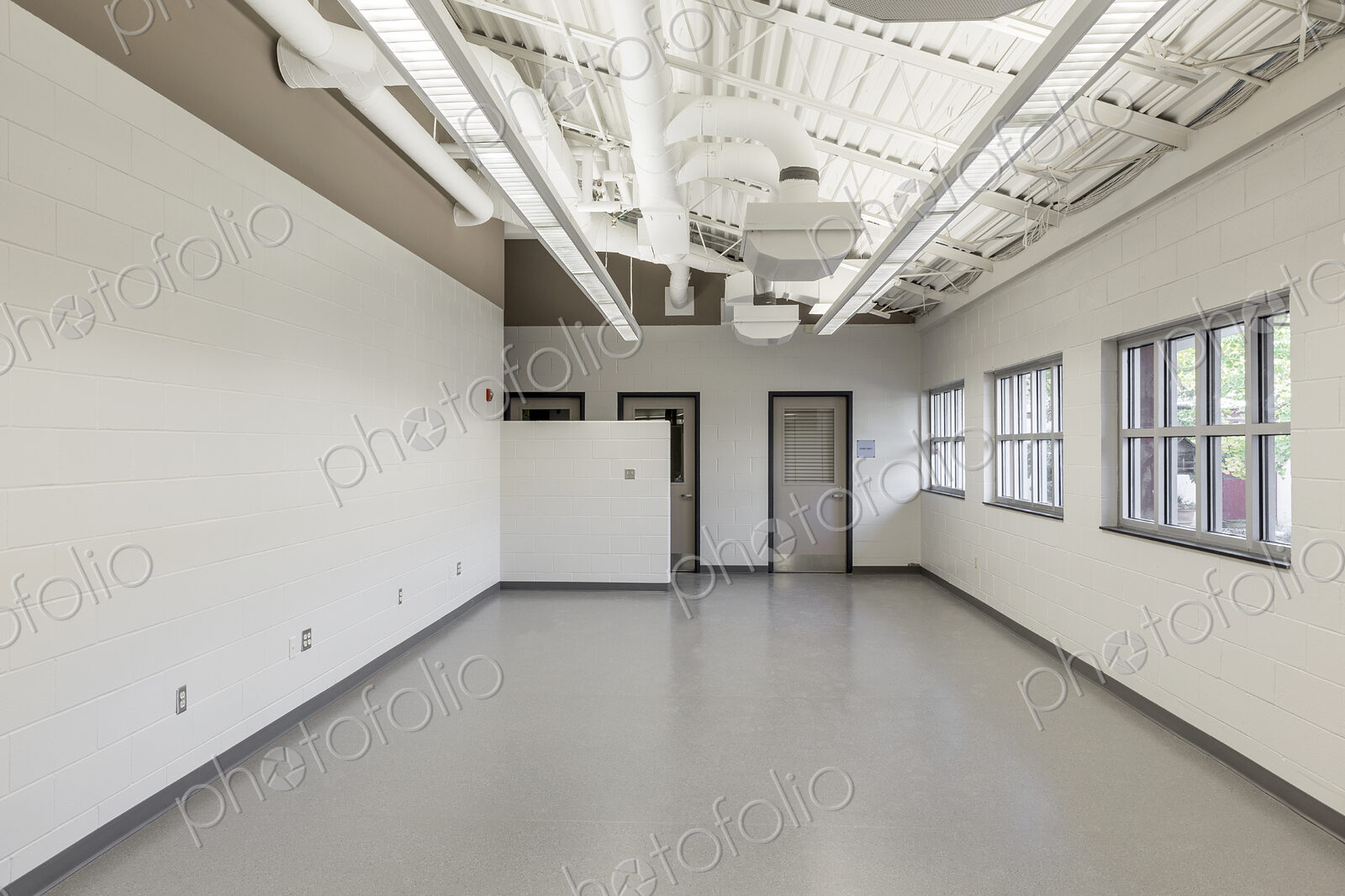 Interior view of a room with white walls and grey vinyl floor in an animal shelter.