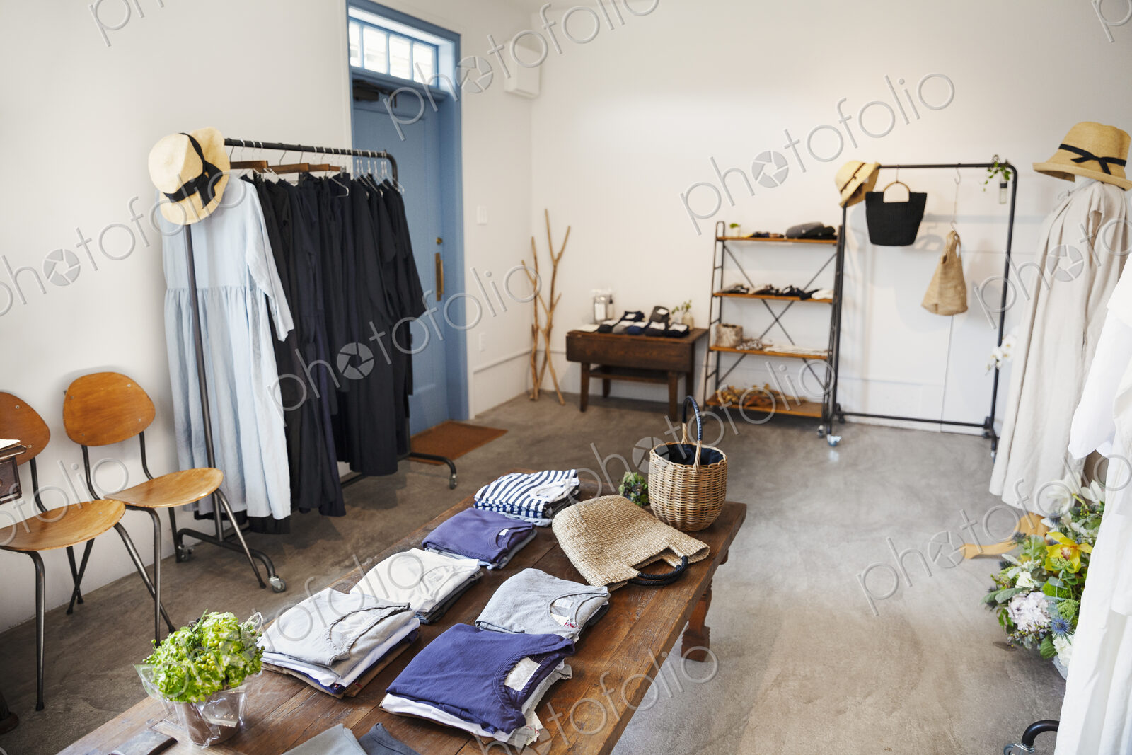 Interior view of a small fashion boutique, with T-Shirts on a coffee table and dresses…