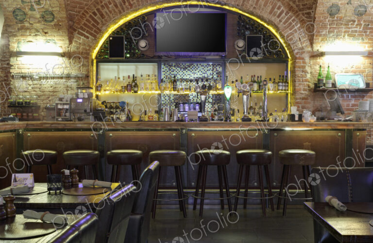 Interior view of bar with big TV screen on wall.