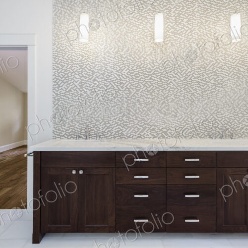 Interior view of bathroom with wooden vanity unit with stainless steel taps and mosaic…