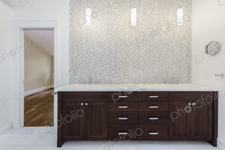Interior view of bathroom with wooden vanity unit with stainless steel taps and mosaic…