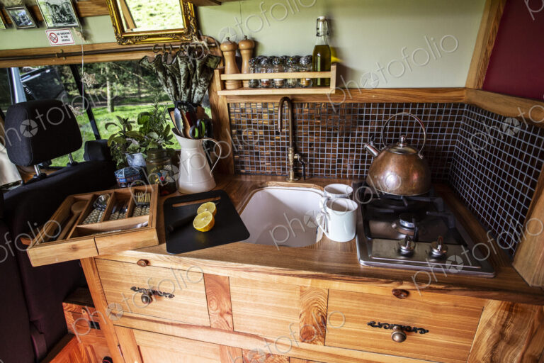 Interior view of camper van with small cooking area and sink.