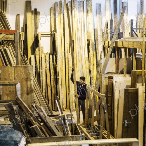 Interior view of warehouse with stacks of wooden planks, young man working. Interior view of warehouse with stacks of wooden planks, young man working.