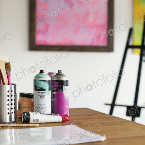 Interior view or art gallery with studio space, easels and cans of spray paint on a table.