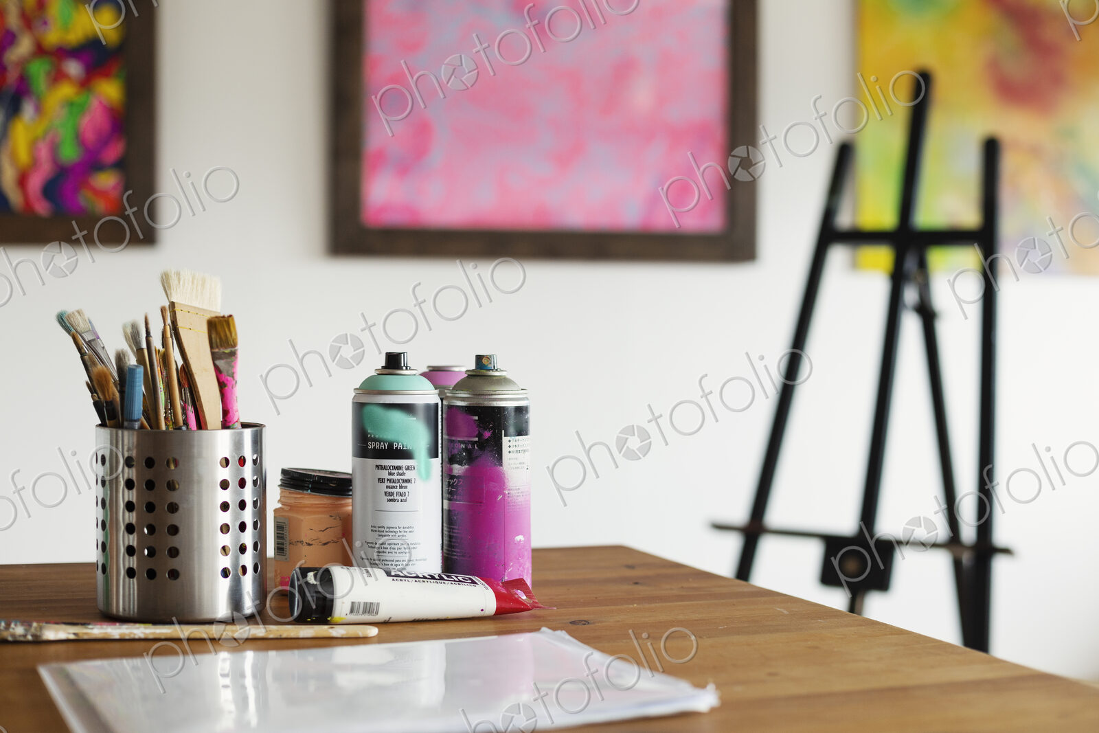 Interior view or art gallery with studio space, easels and cans of spray paint on a table.