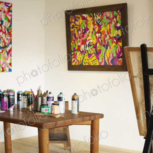 Interior view or art gallery with studio space, easels and cans of spray paint on a table.