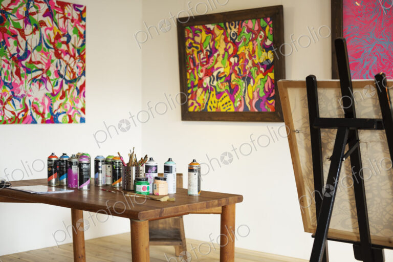 Interior view or art gallery with studio space, easels and cans of spray paint on a table.