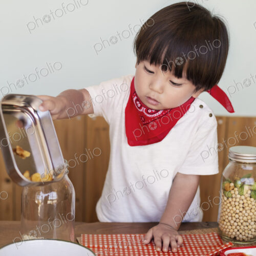 Japanese boy standing at a table in a farm shop, helping prepare food. Japanese boy standing at a table in a farm shop, helping prepare food.