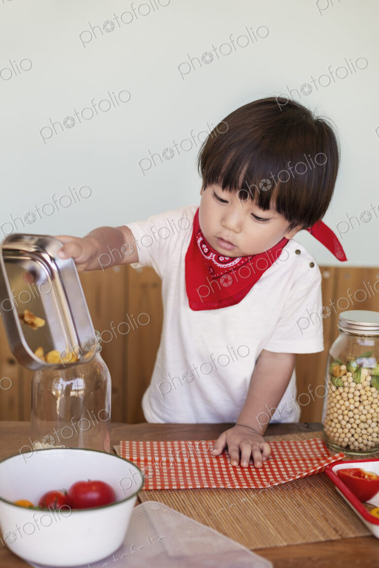 Japanese boy standing at a table in a farm shop, helping prepare food.