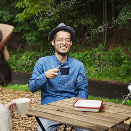 Japanese man and two women sitting outdoors at a table, drinking coffee. Japanese man and two women sitting outdoors at a table, drinking coffee.