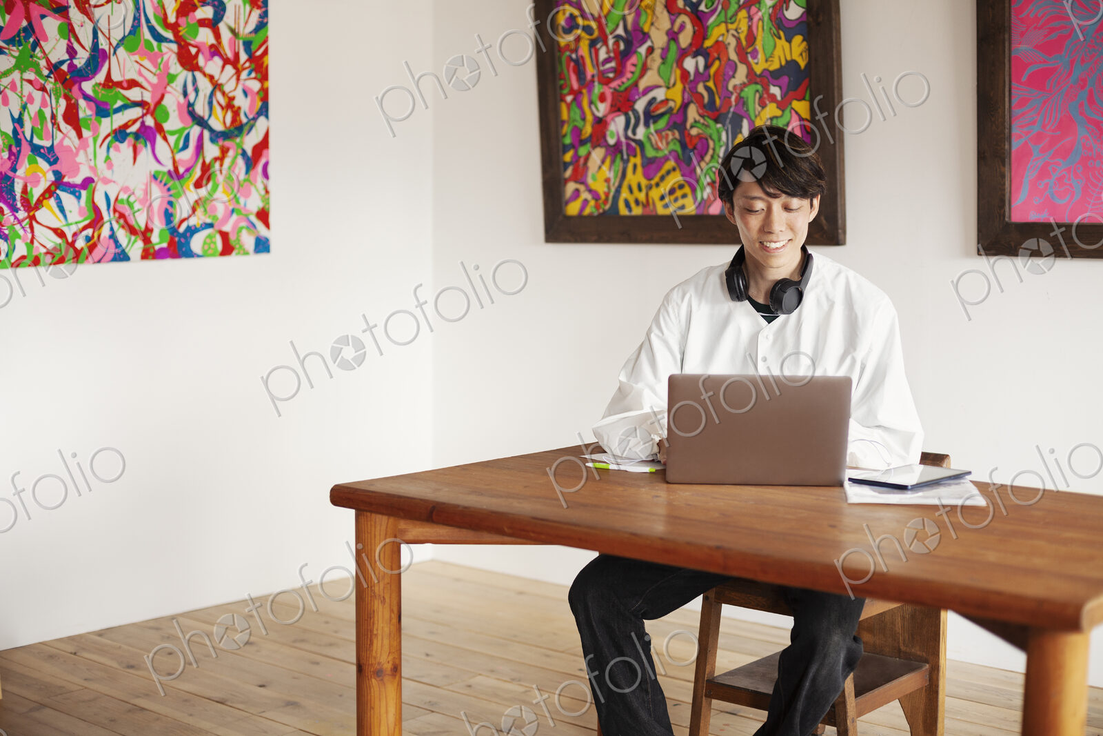 Japanese man sitting at a table in an art gallery, looking at laptop computer.