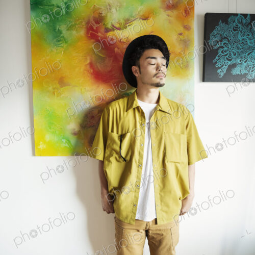 Japanese man standing in front of abstract painting in an art gallery.